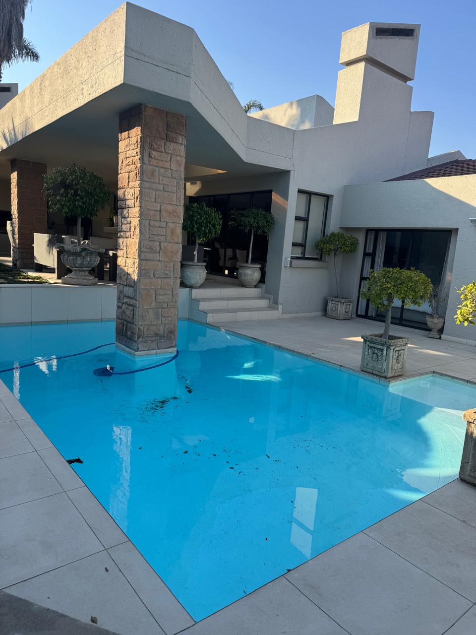 Completed swimming pool with clear blue water beside a modern home